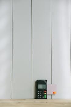 A sleek payment terminal with buttons against a white wooden background, ideal for finance concept.